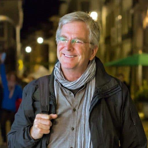 Rick Steves smiling and carrying a bag
